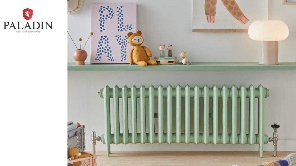 A mint green radiator sits below a shelf with toys, a lamp, and a decorative “PLAY” sign against a white wall.